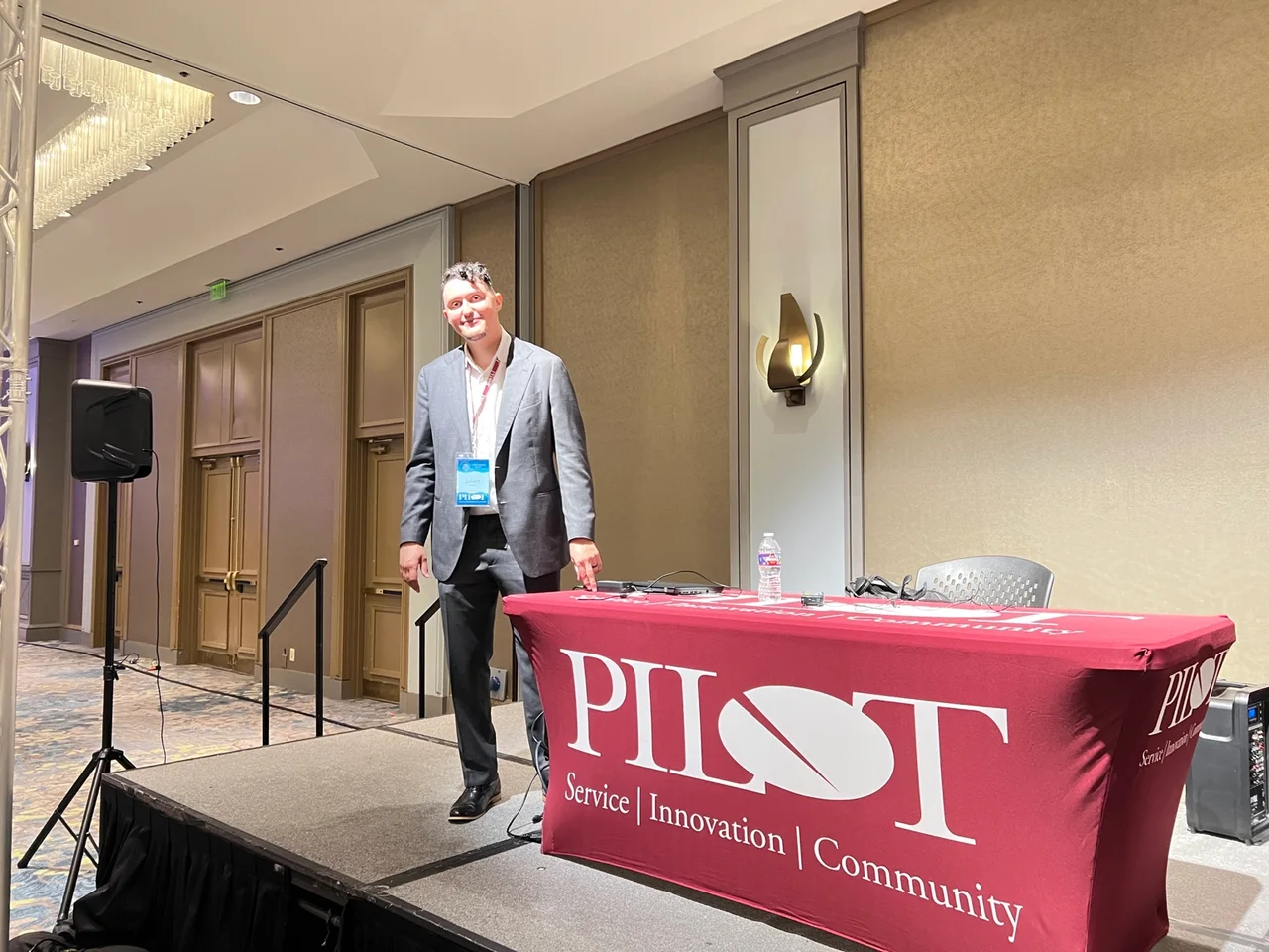 Julian Badillo standing on stage after speaking, beside a table bearing the Pilot logo