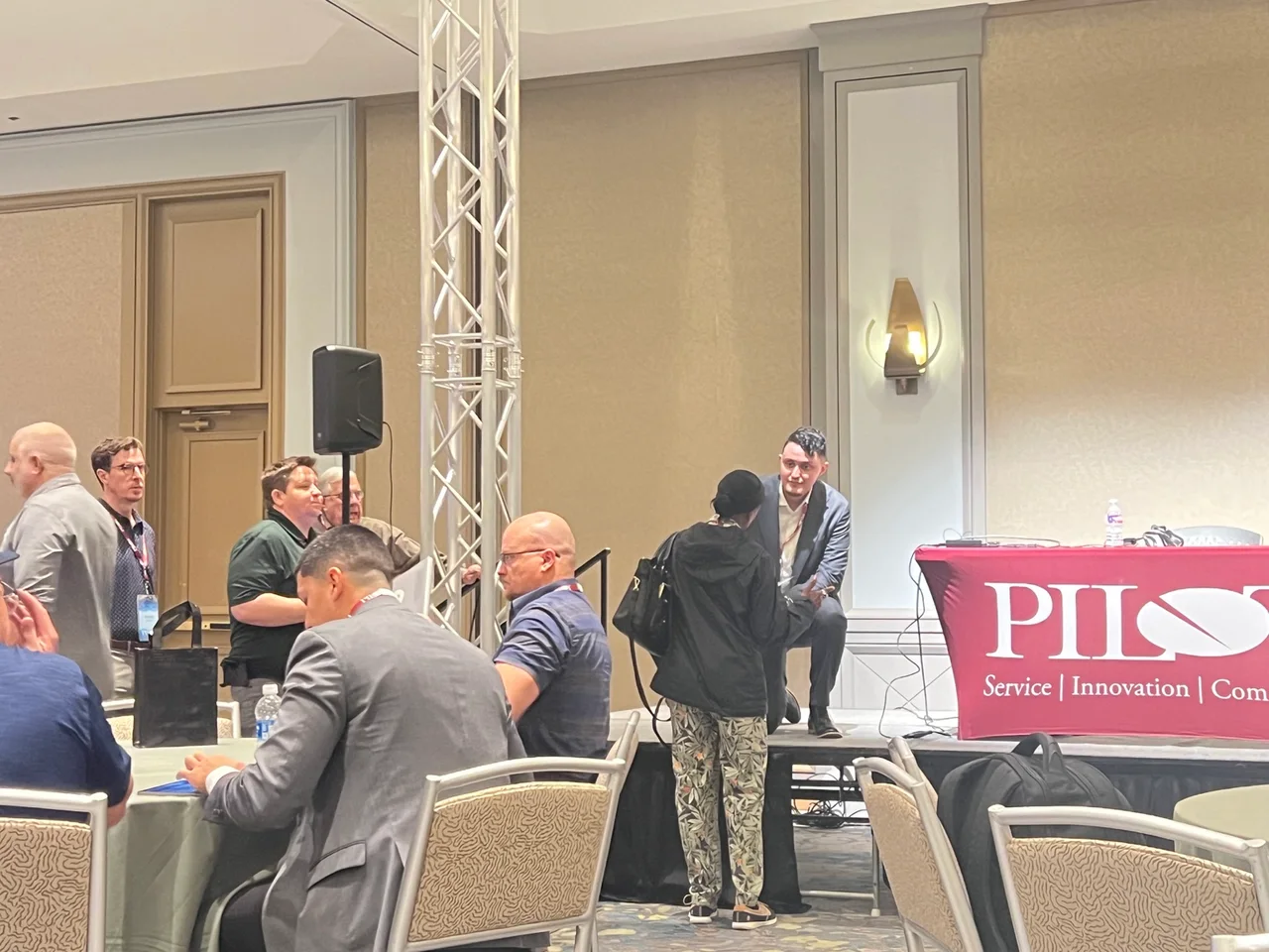 Julian Badillo kneeling at the edge of the stage to speak with an attendee after his presentation